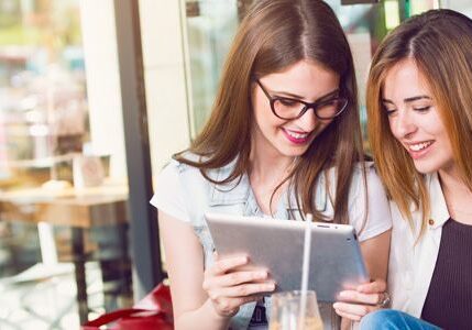Women enjoying a tablet at a café